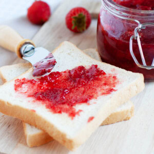 Strawberry jam in a jar with bread.