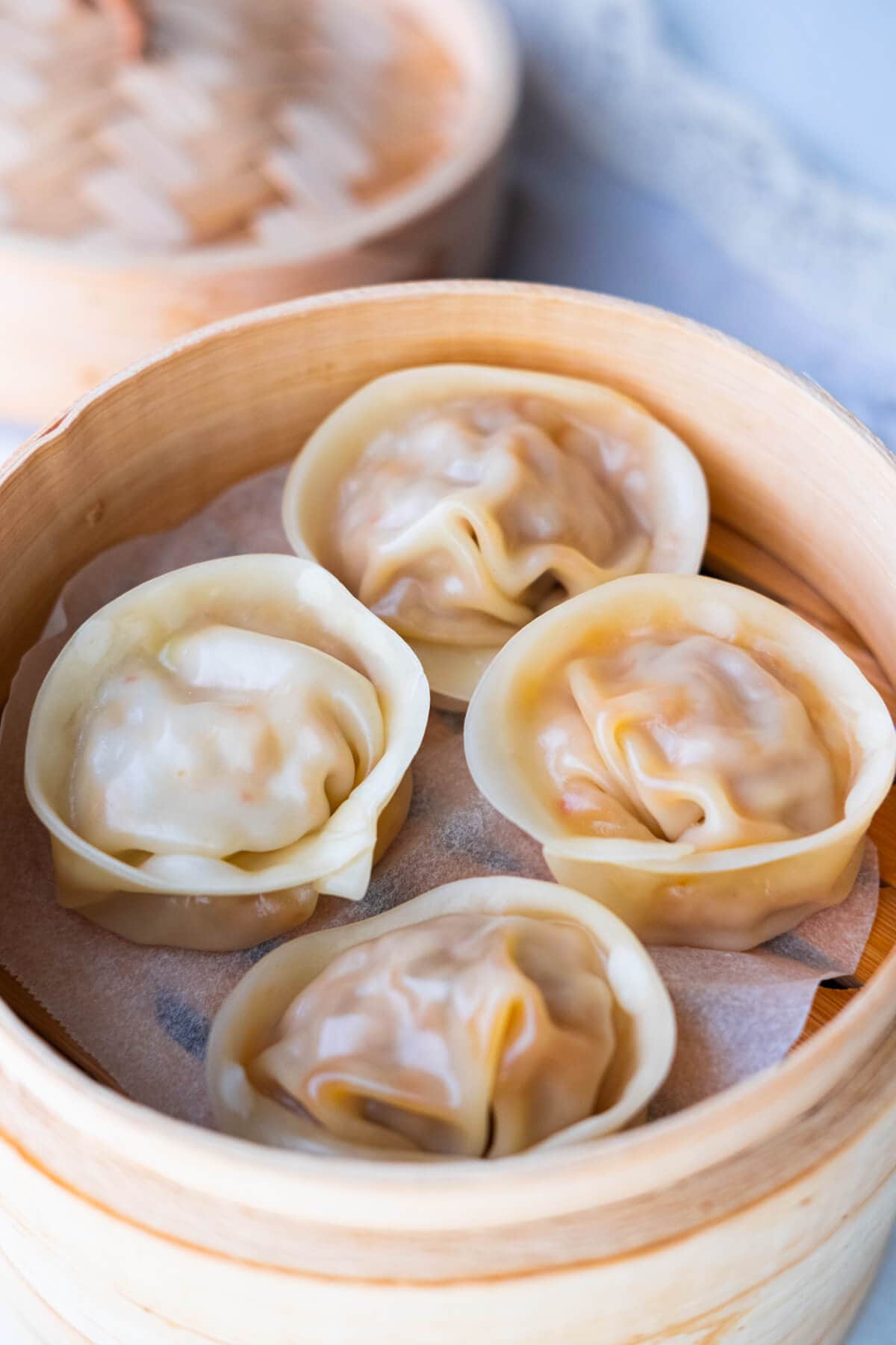 Easy Korean homemade kimchi dumplings steamed and served in a bamboo steamer.