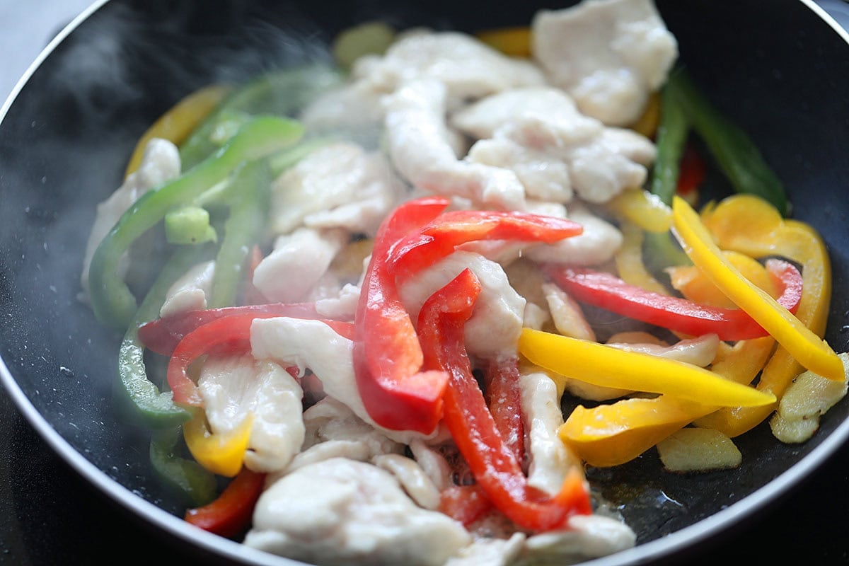 Chicken and bell peppers in a wok.