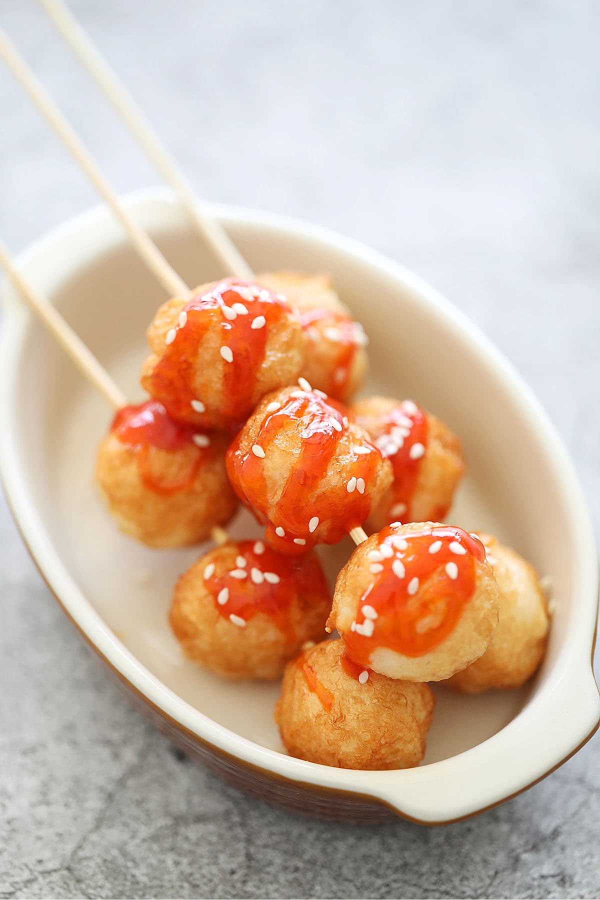 Fried cuttlefish balls topped with sesame seeds and chili sauce.