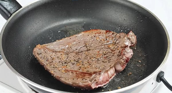 Seasoned skirt steak on a skillet.