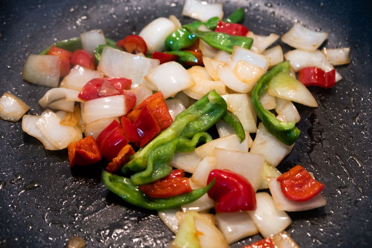 Onion and bell peppers in skillet.