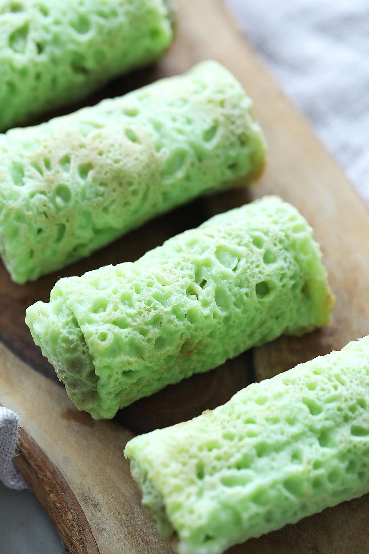 Nyonya Kuih dadar or kuih ketayap (kuih tayap) served on a wooden board.