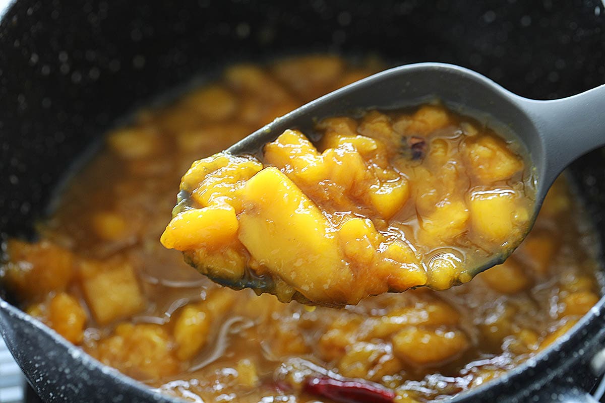 Sweet mango chutney scooped up with a ladle.