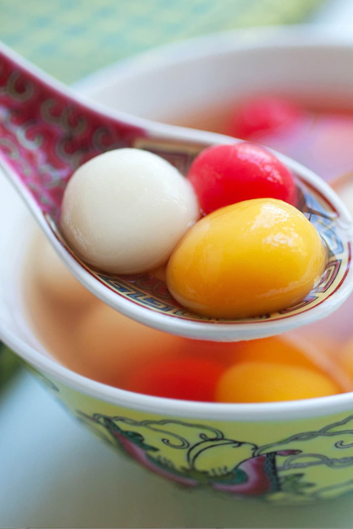 Three colorful tang yuan dessert on a Chinese spoon.