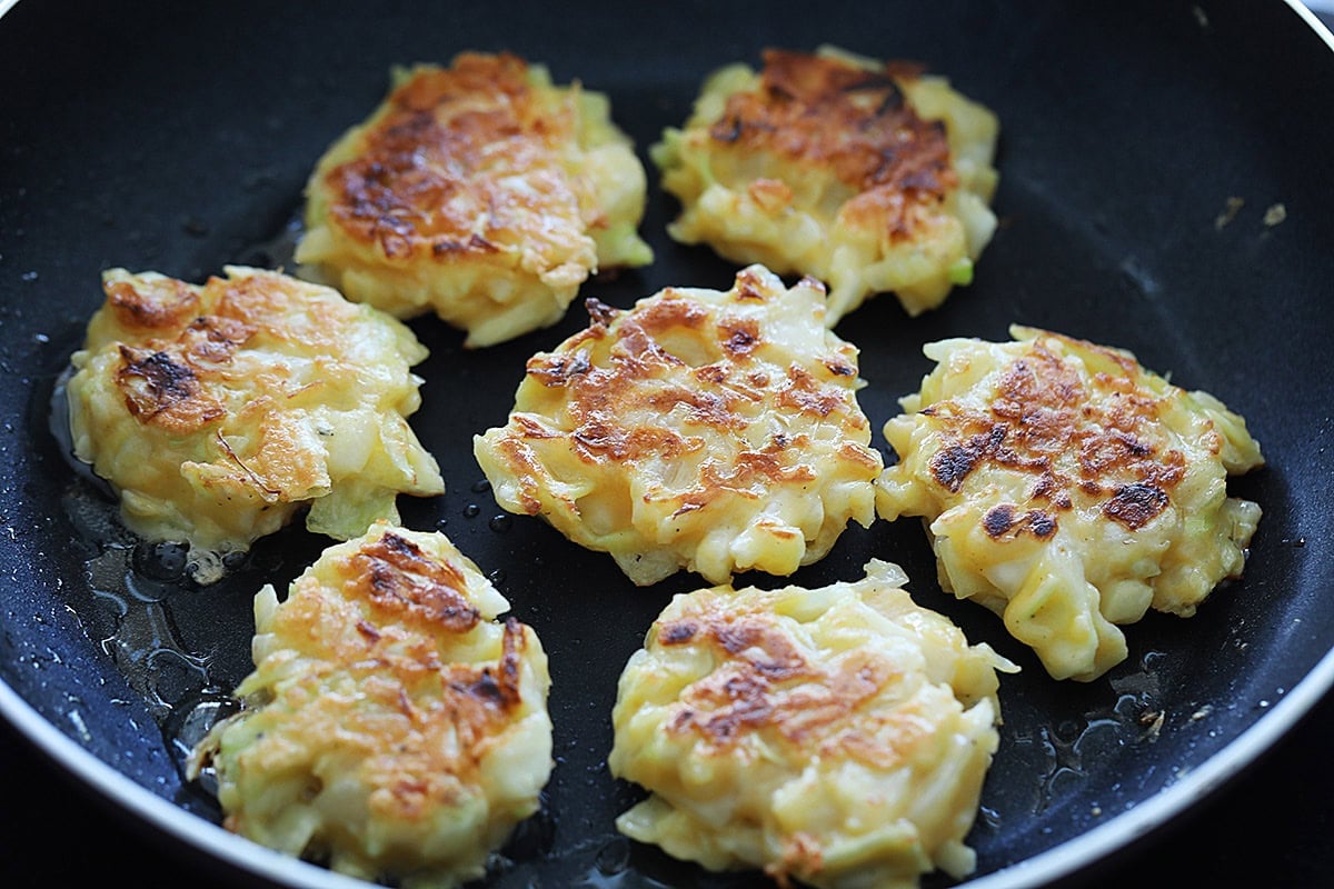 Cooking cabbage patties on a skillet.