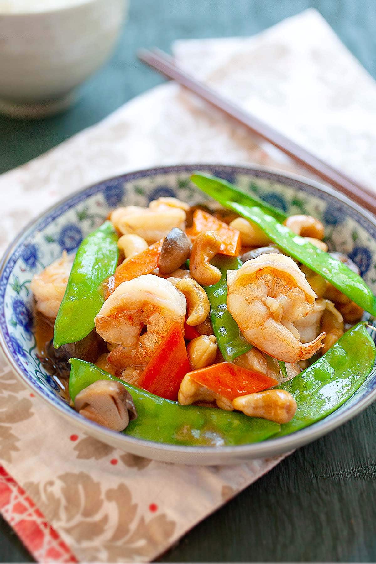 Cashew shrimp stir fry served in a Chinese plate with a pair of chopsticks.