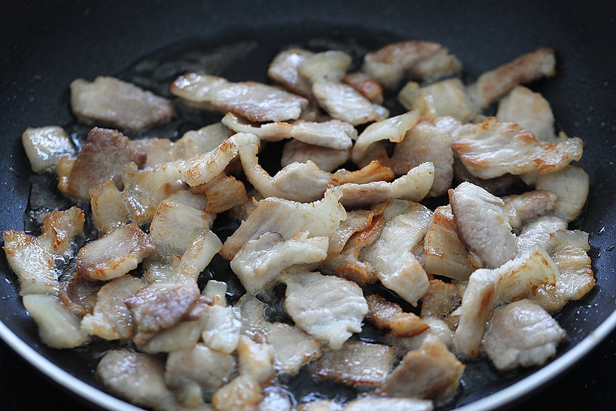 Slightly browned pork belly in a wok.