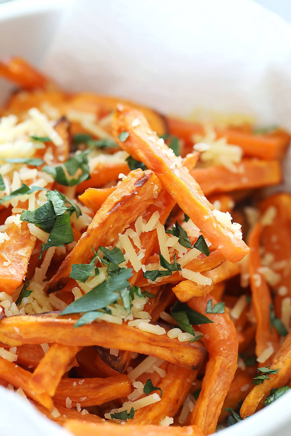 Golden brown sweet potato fries in a bowl, a delicious air fryer recipe finished with Parmesan and parsley.