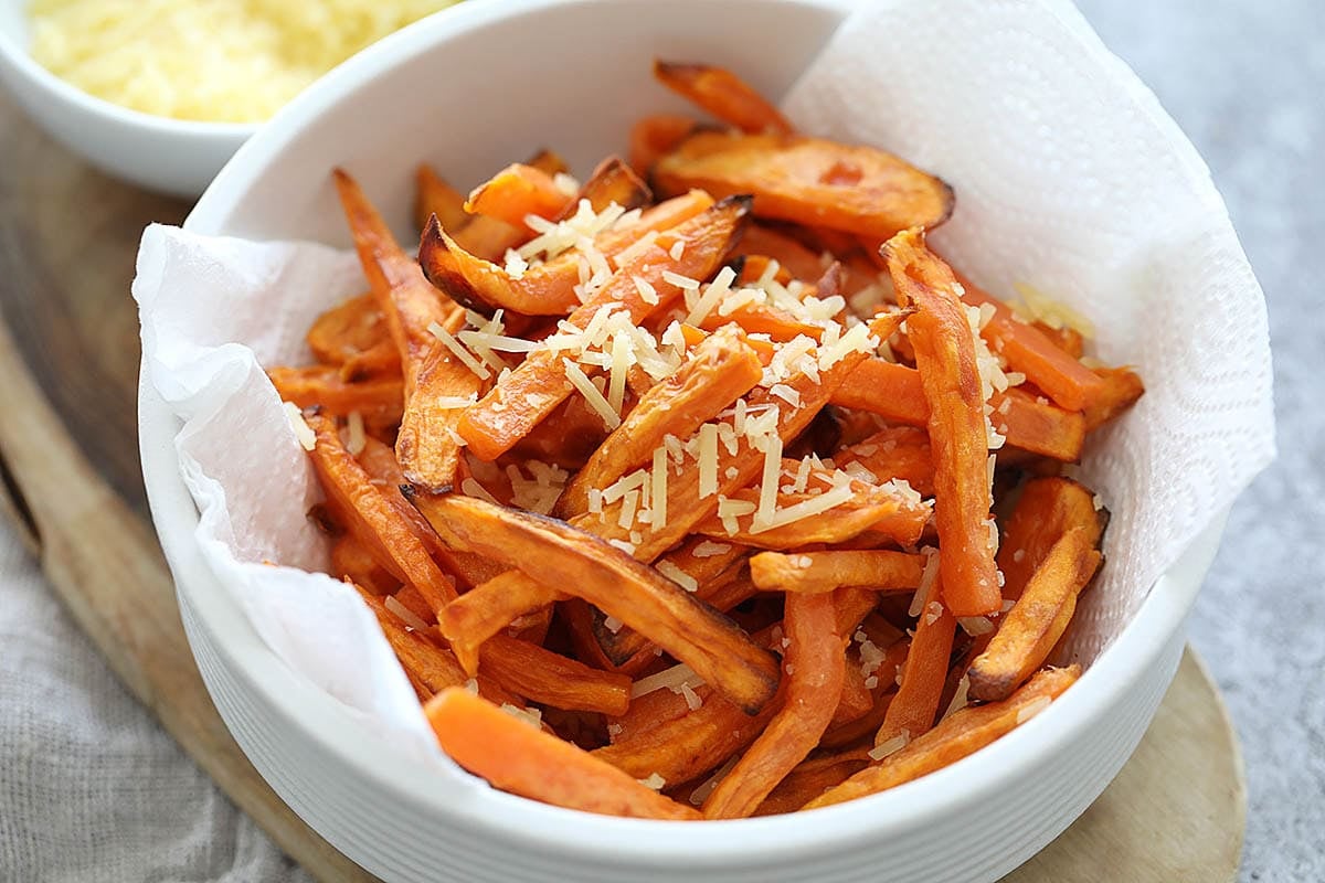 Sweet potato fries in a bowl, topped with Parmesan cheese.