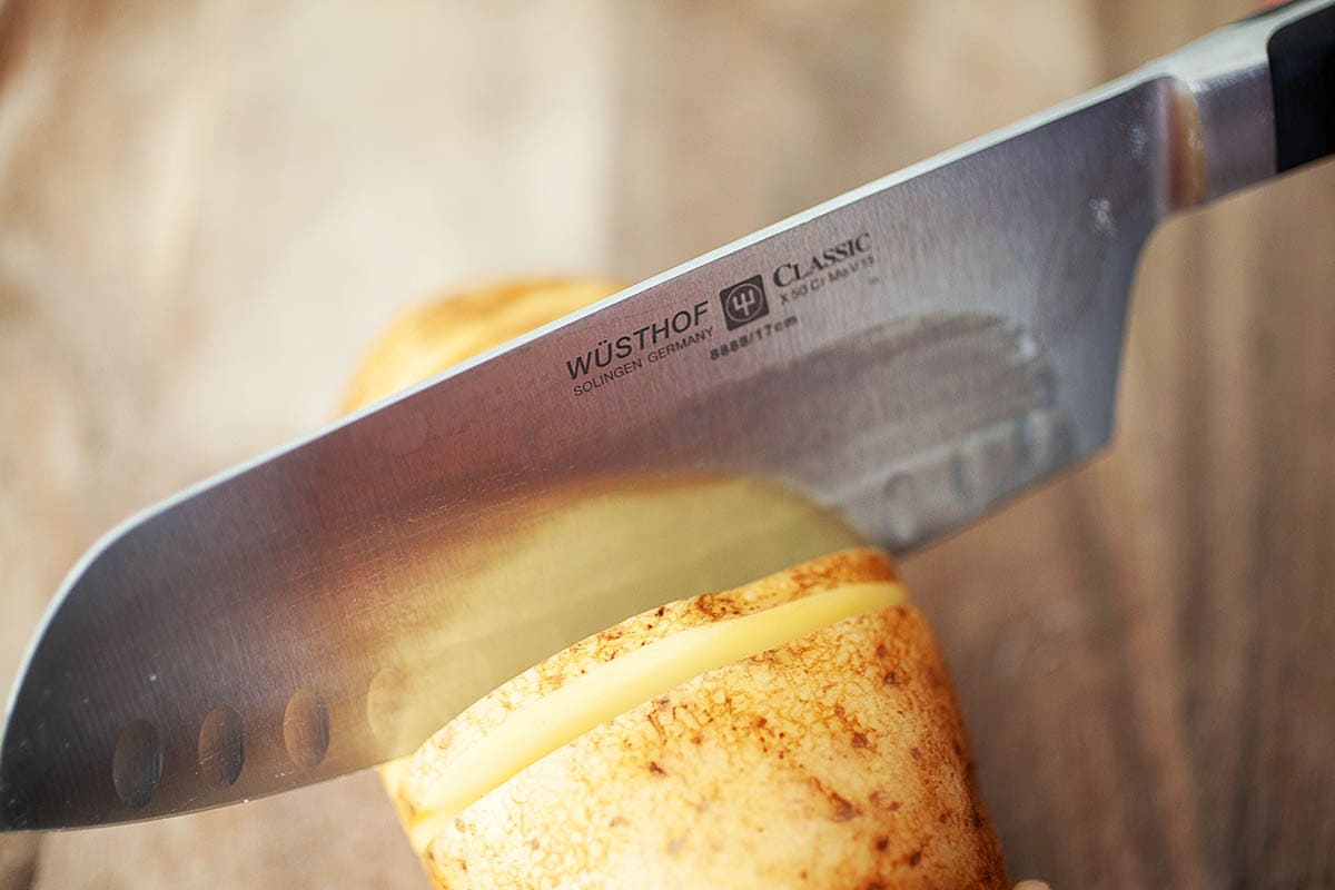 Slicing a potato with a knife, creating even cuts.