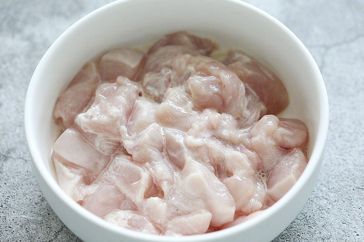 Chicken marinated with cornstarch in a bowl.