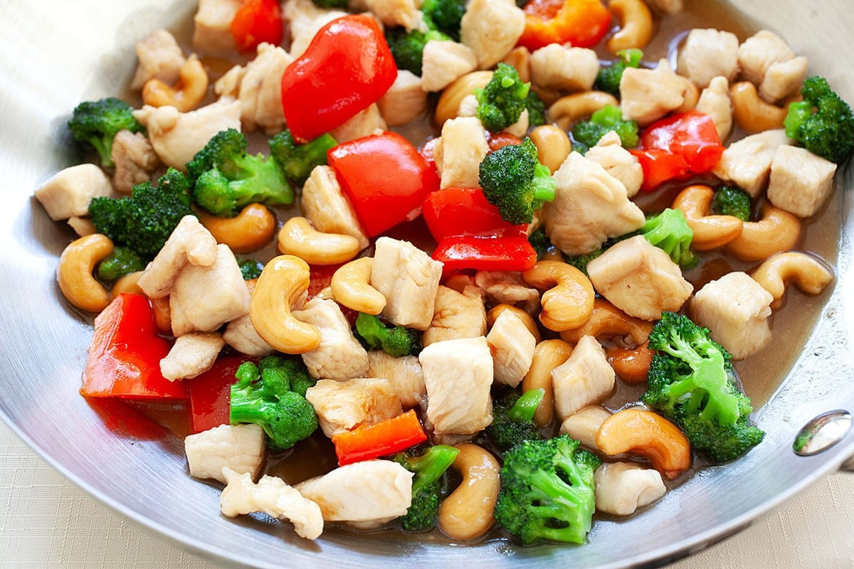 Honey cashew chicken with stir fried chicken breast, crunchy cashew nuts, and colorful veggies, coated in a savory sauce in a skillet.