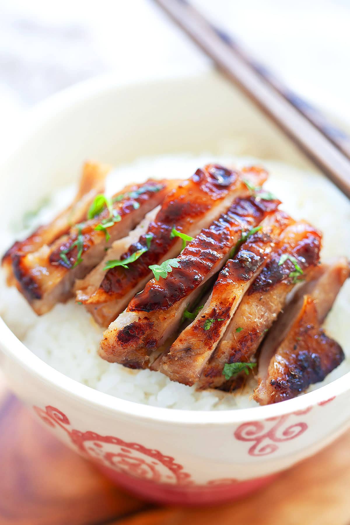 Sliced lemongrass chicken served on top of a bowl of rice.