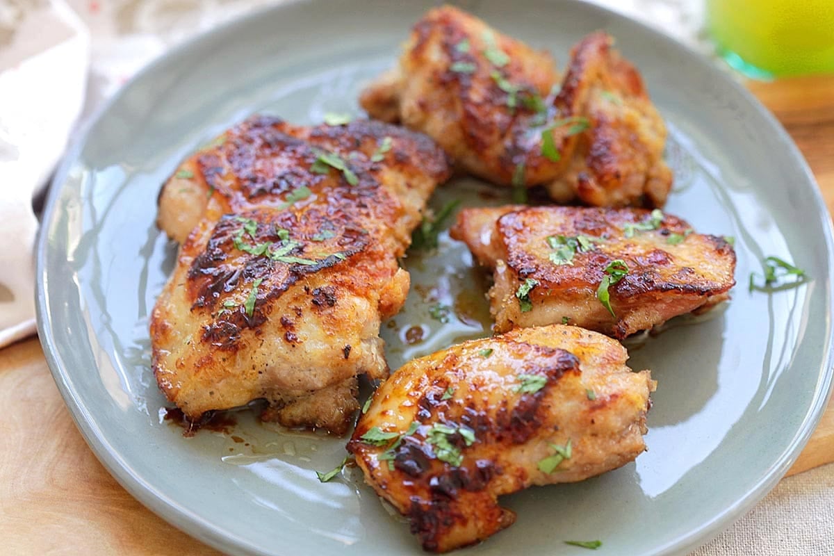 Pan-fried chicken marinated with lemongrass, honey, and spices, served on a plate.