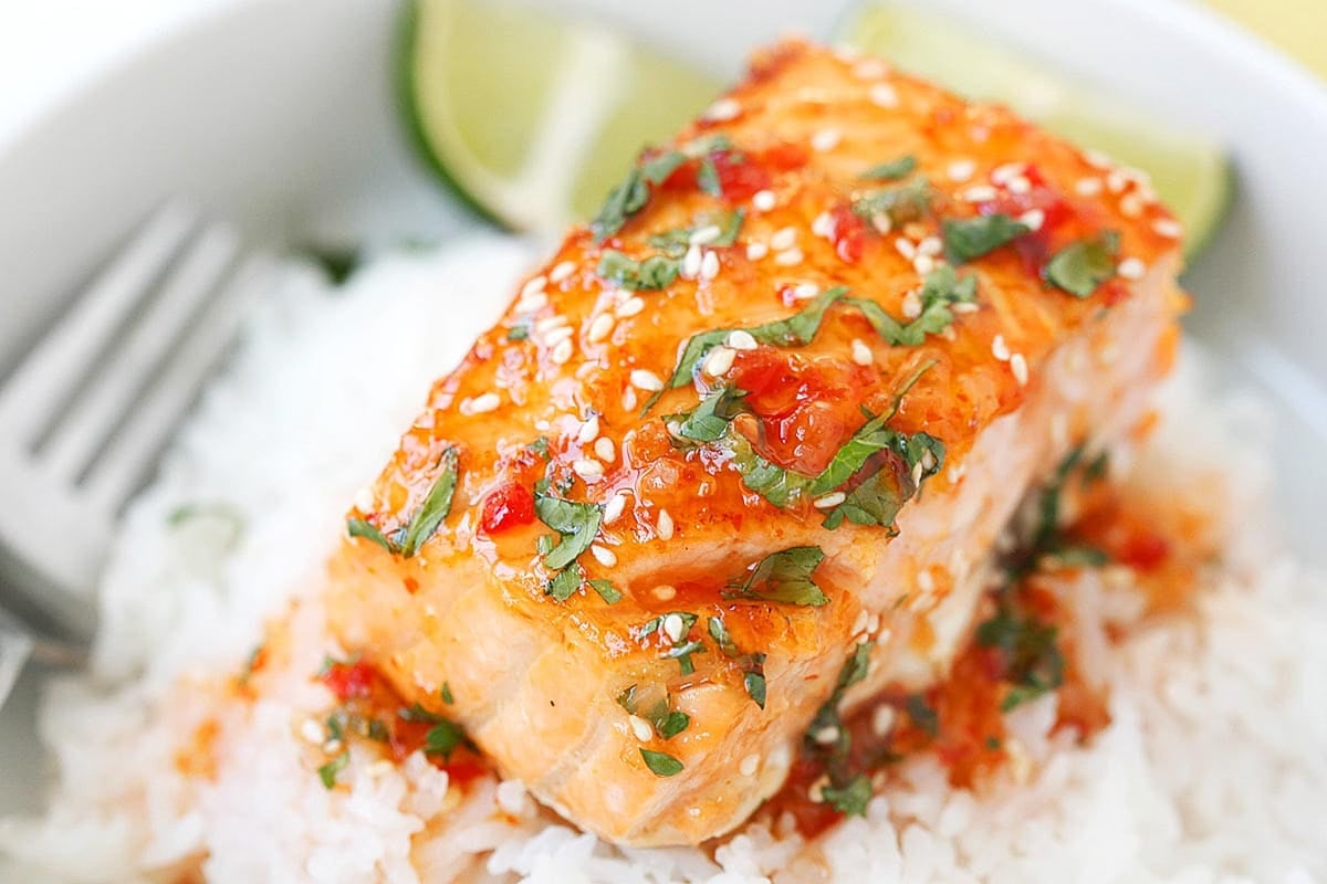 Sweet chili salmon served with rice and lime wedges.