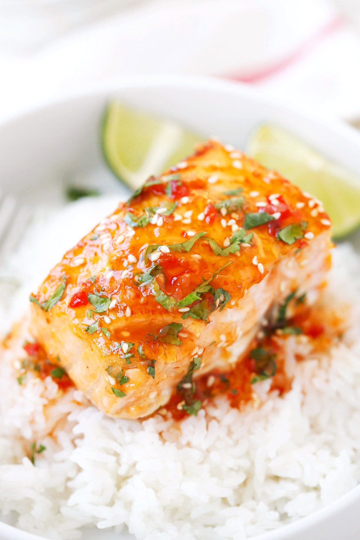 Pan fried sweet chili salmon with rice, lime wedges, and a sprinkle of sesame seeds.