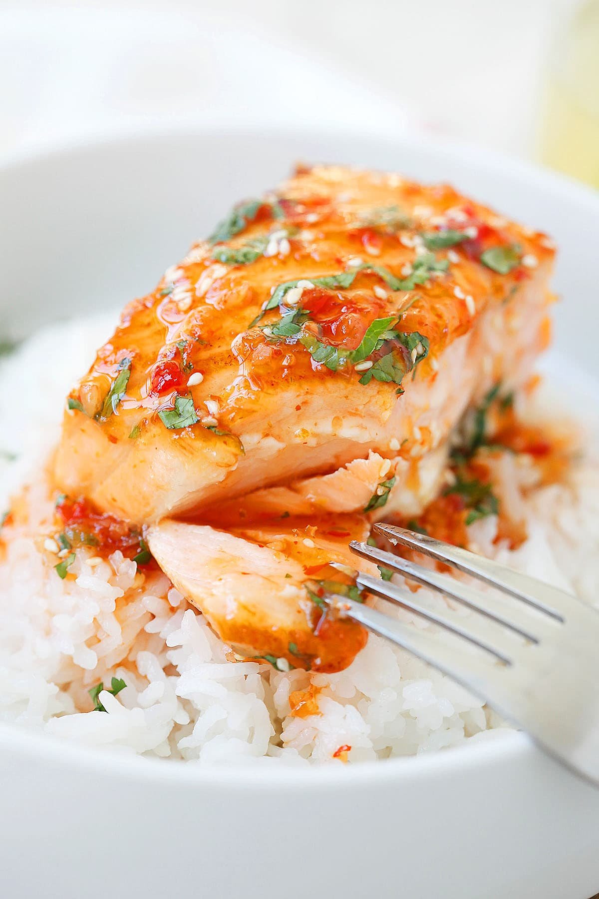 Flaky sweet chili salmon with a sticky glaze, topped with fresh cilantro, served over a bowl of white rice.