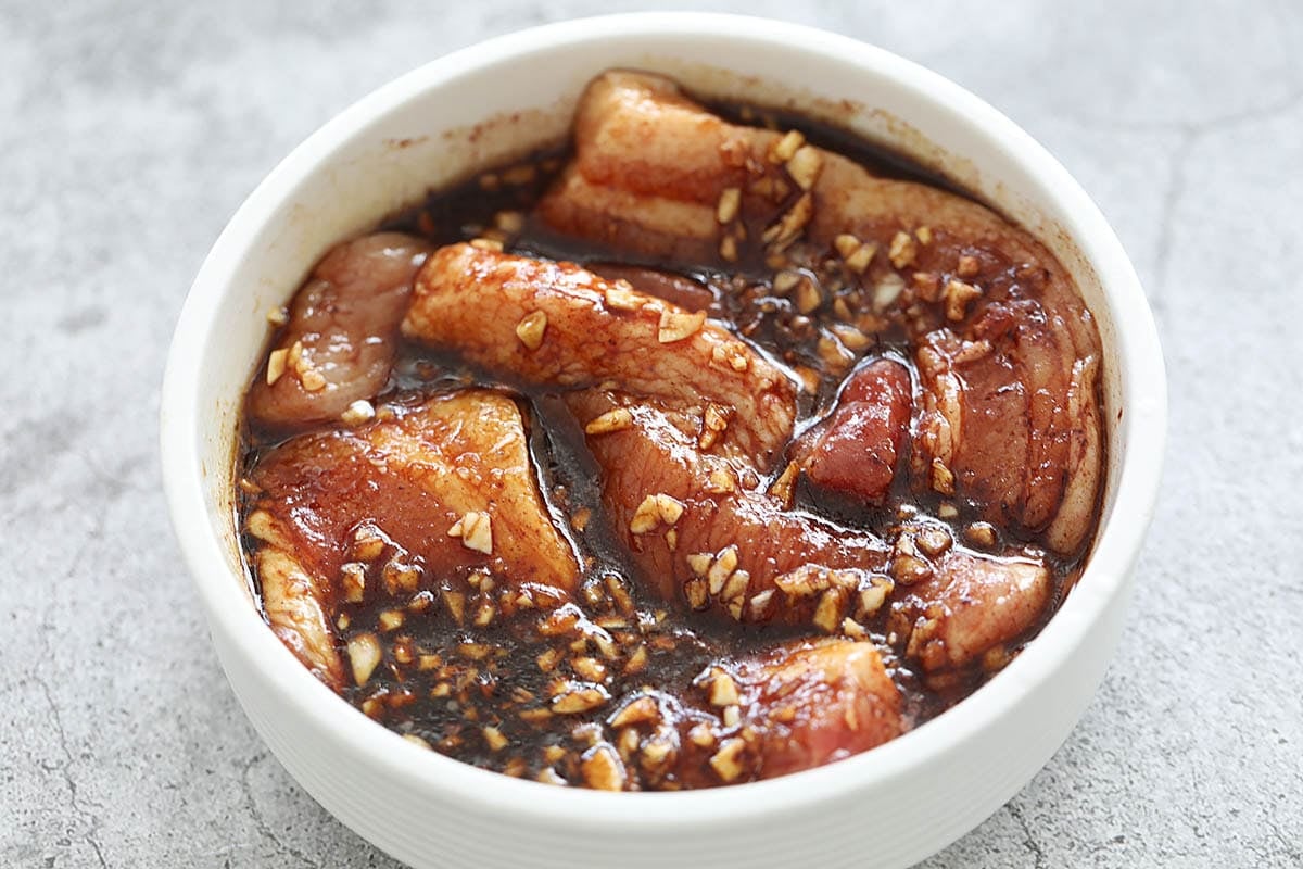 Pork belly marinated with char siu sauce in a bowl.