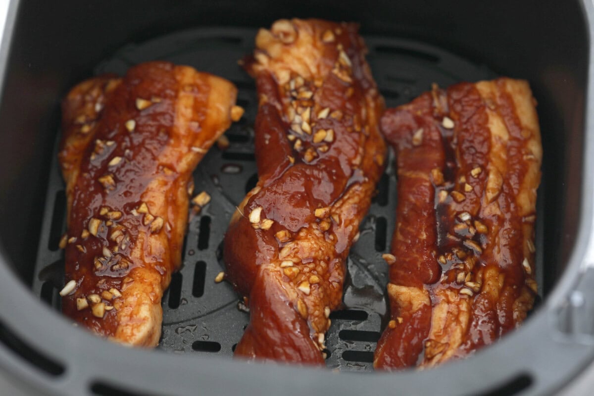 Marinated pork belly placed in the air fryer basket.