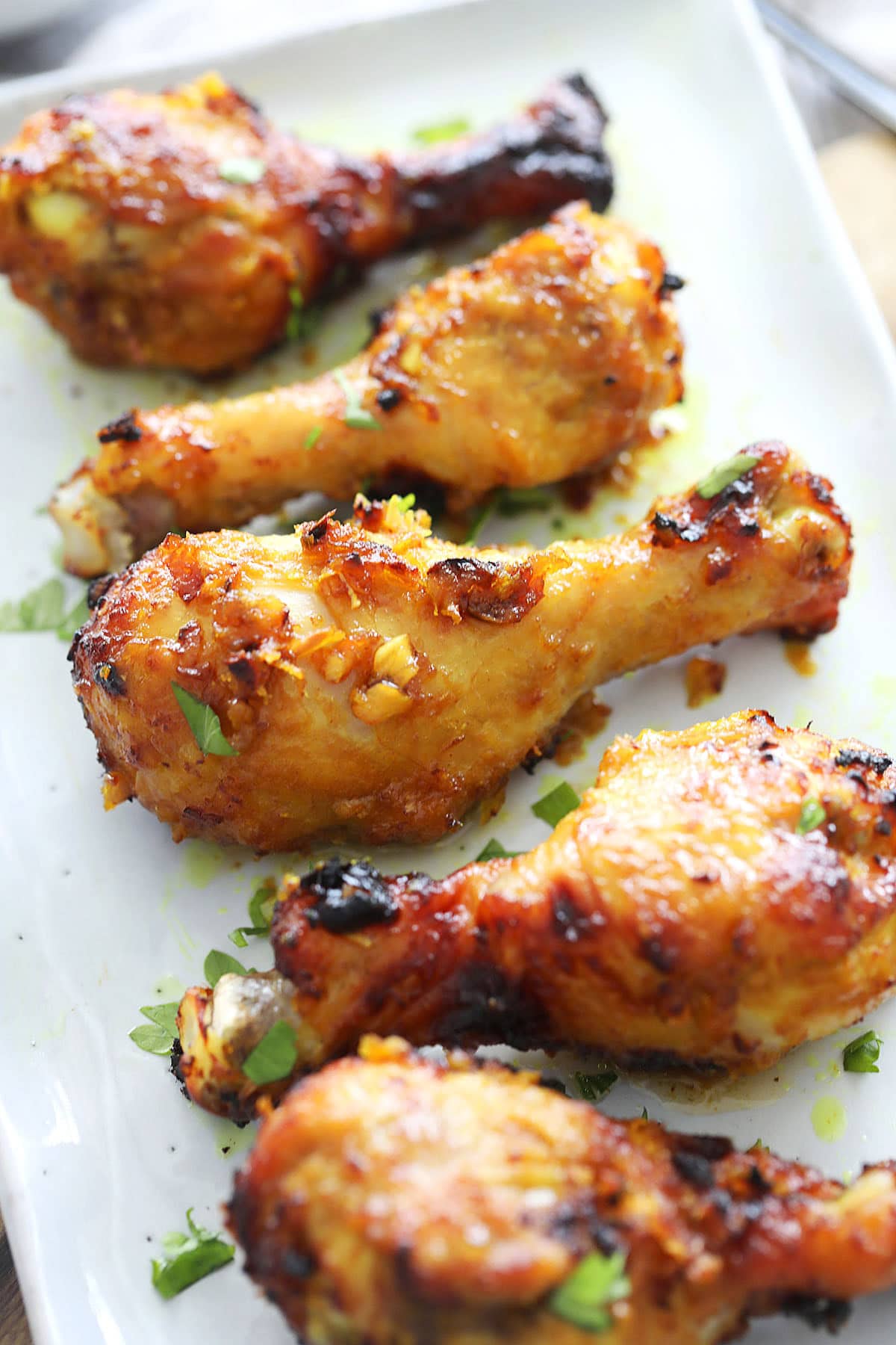 Crispy, glossy air fryer chicken drumsticks garnished with fresh parsley.