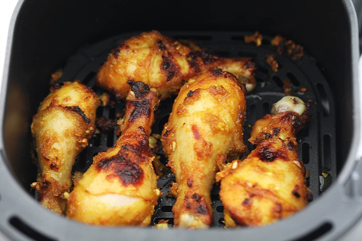 Golden air fryer chicken drumsticks in the air fryer basket.