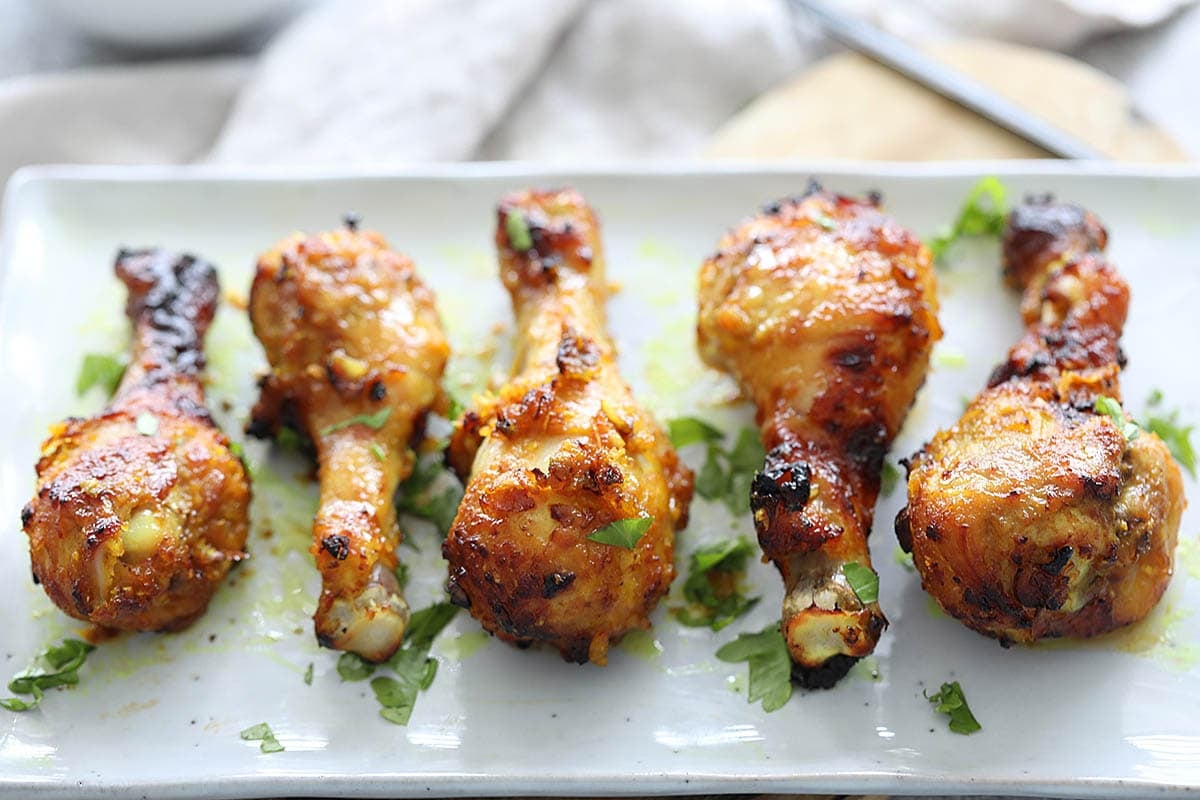 Golden-brown air fryer chicken legs served on a plate, garnished with parsley.