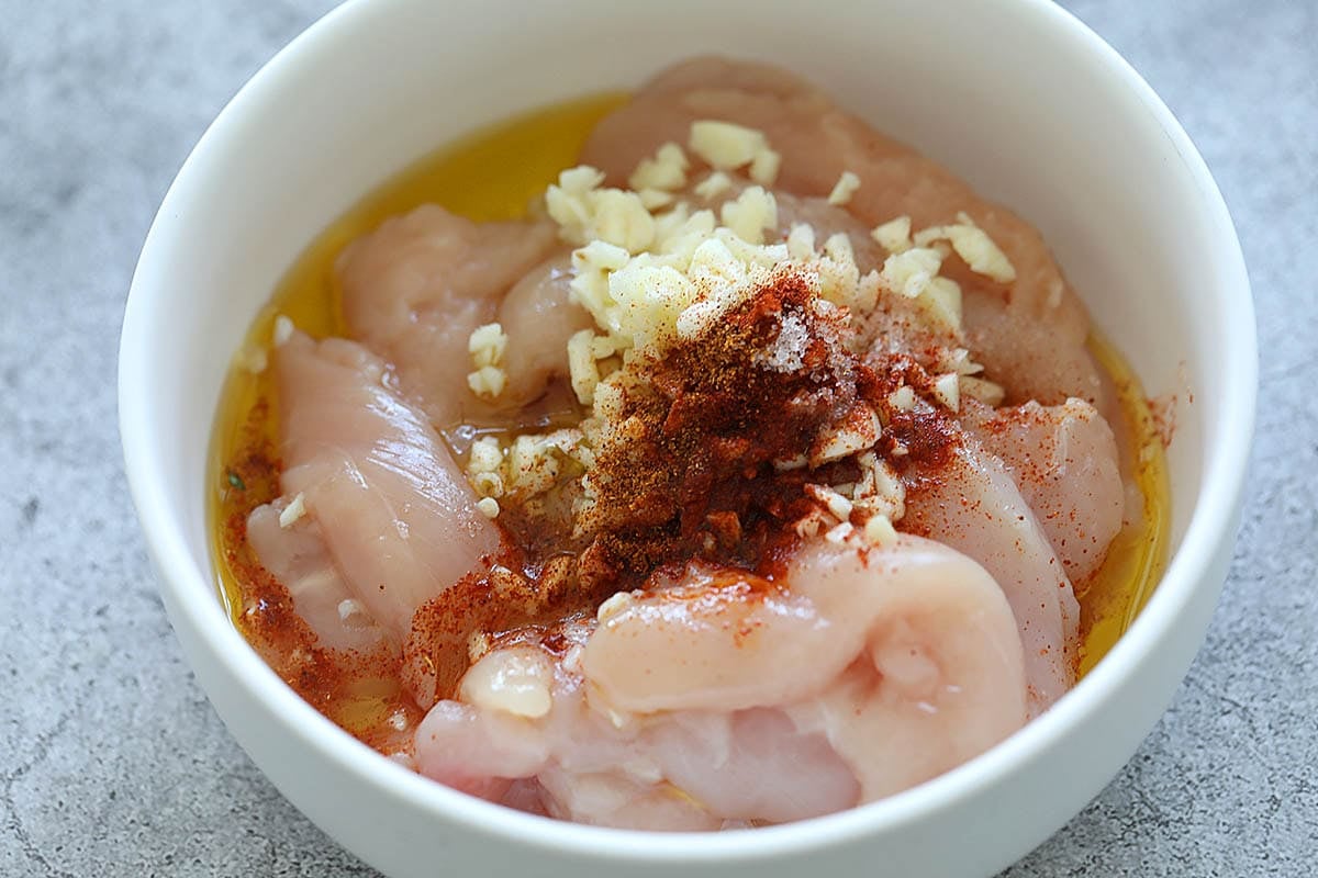 Chicken tenders with marinade ingredients in a bowl.