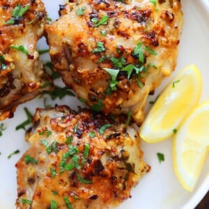 Air fryer garlic parmesan chicken thighs with lemon wedges on the side.