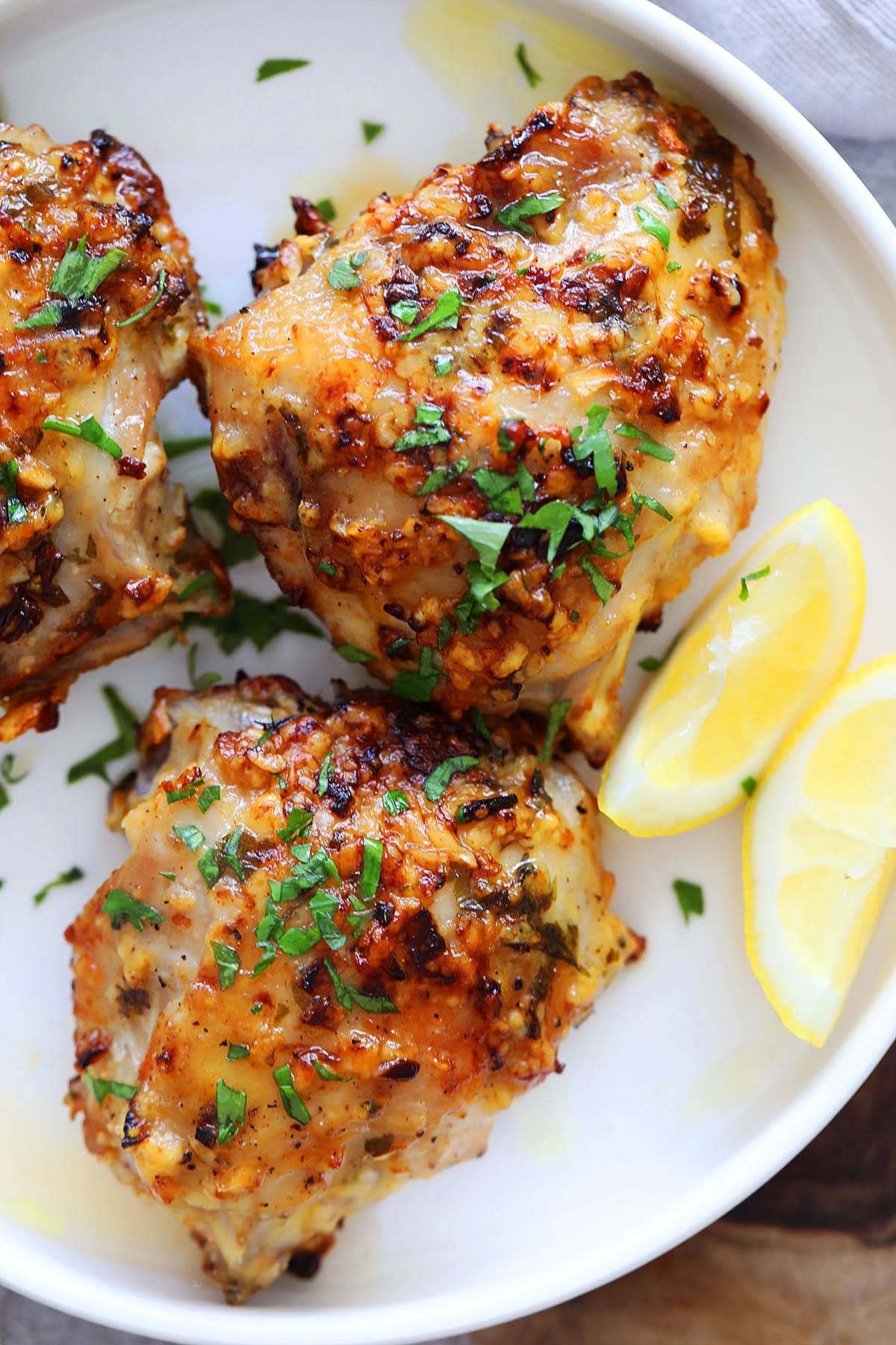 Air fryer garlic parmesan chicken thighs with lemon wedges on the side.