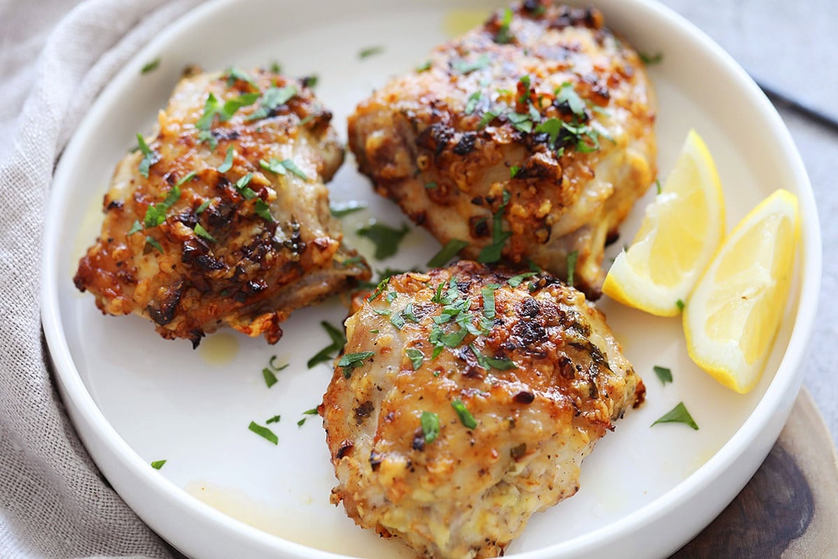 Crispy air fryer garlic parmesan chicken garnished with parsley and served with lemon wedges.