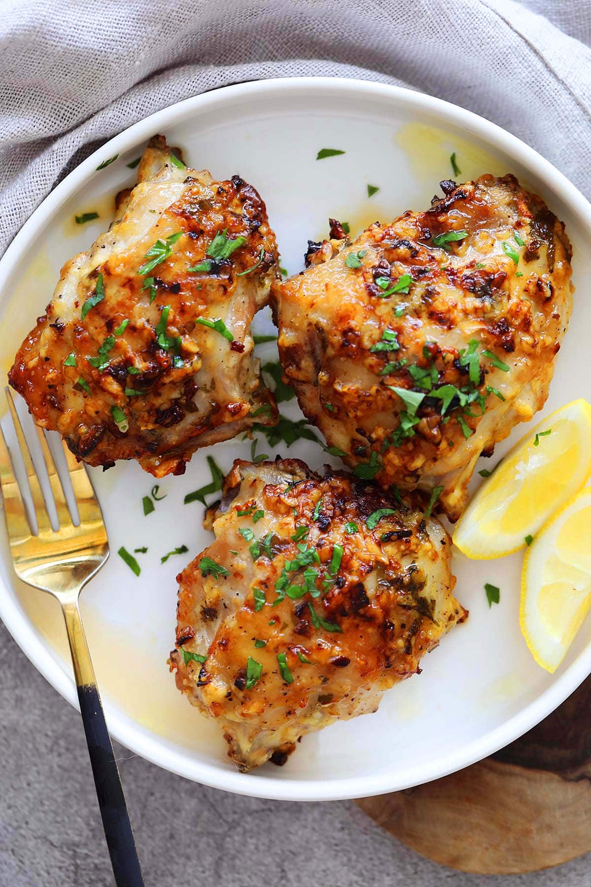 Air fryer garlic parmesan chicken, topped with parsley, served on a plate.