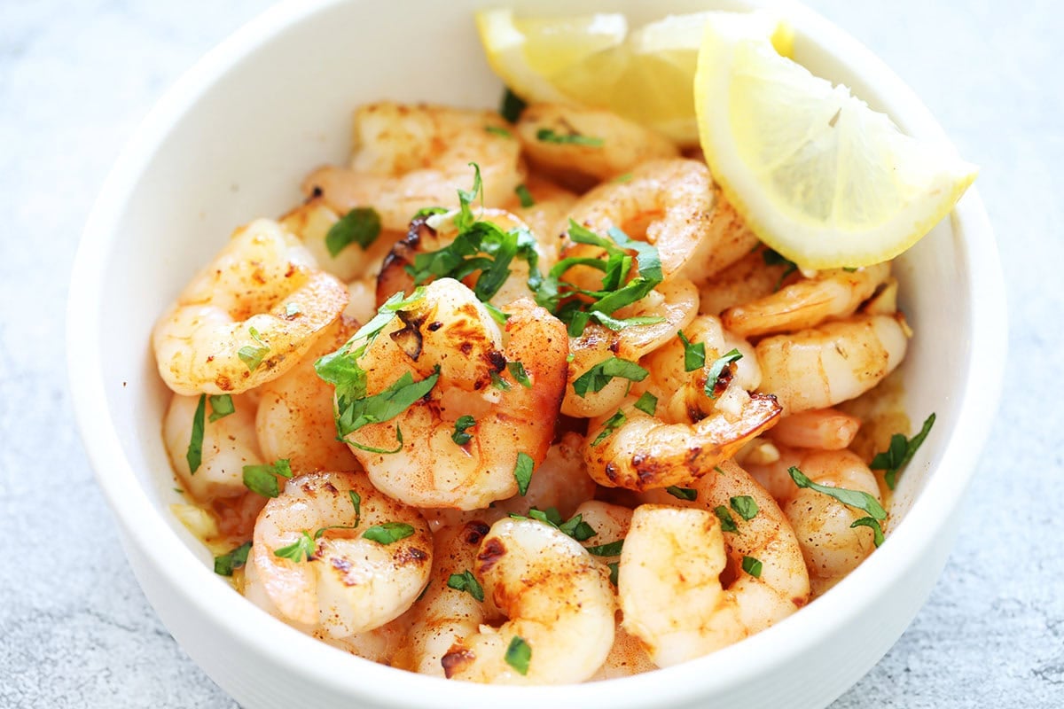 Honey garlic shrimp made in an air fryer, garnished with parsley, and served with lemon wedges.