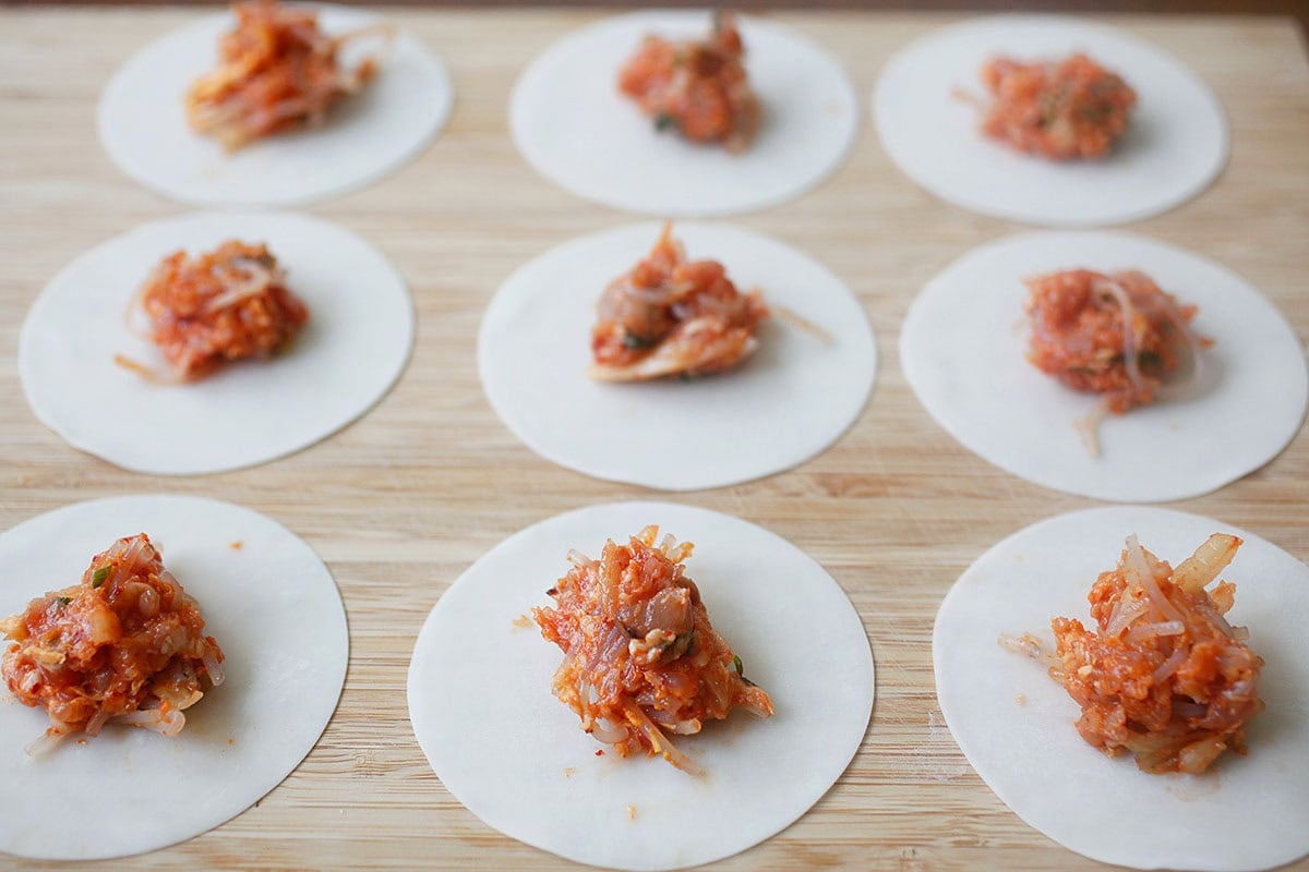 Kimchi mandu filling placed on dumpling wrappers.