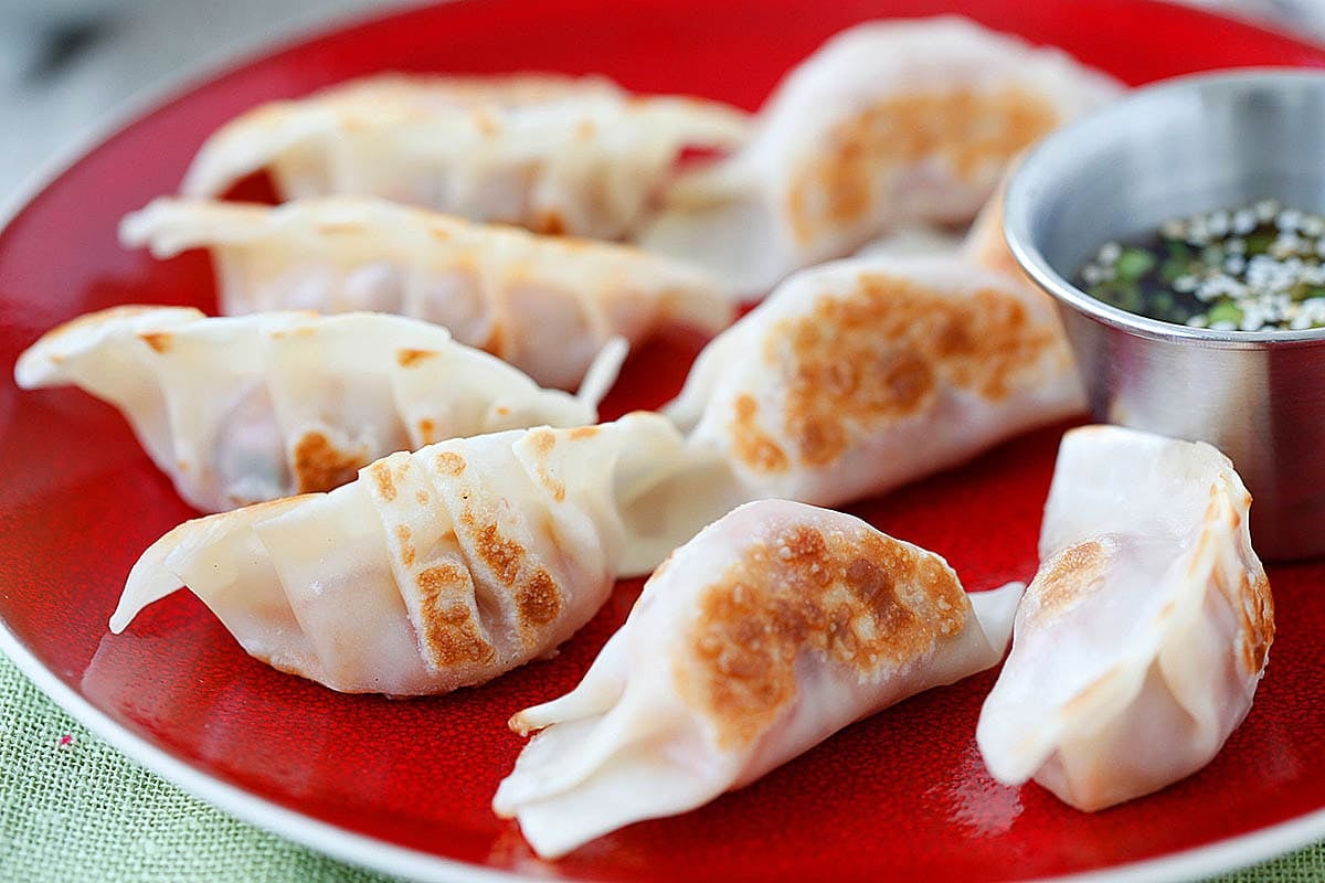 Pan fried kimchi dumplings served with dipping sauce.