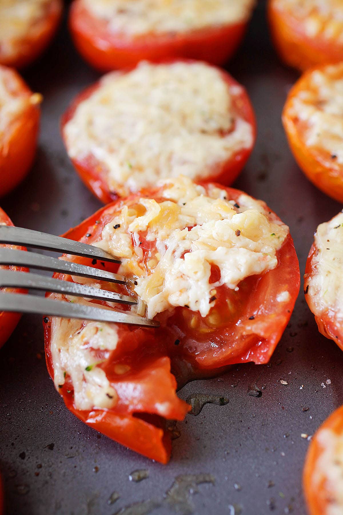 Parmesan baked Roma tomatoes pierced with a fork.