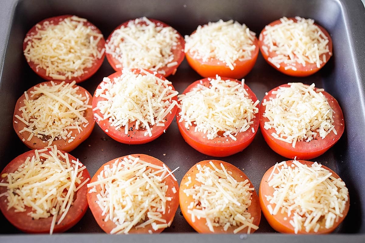 Tomatoes topped with Parmesan cheese in a baking dish.