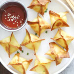 Air fryer crab rangoon served on a plate with a side of sweet and sour sauce.