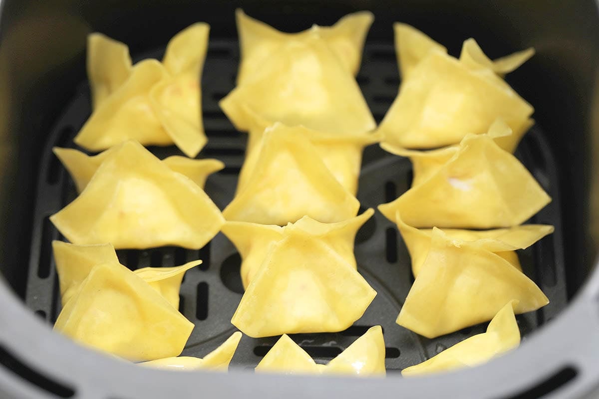 Uncooked crab rangoon in the air fryer basket.