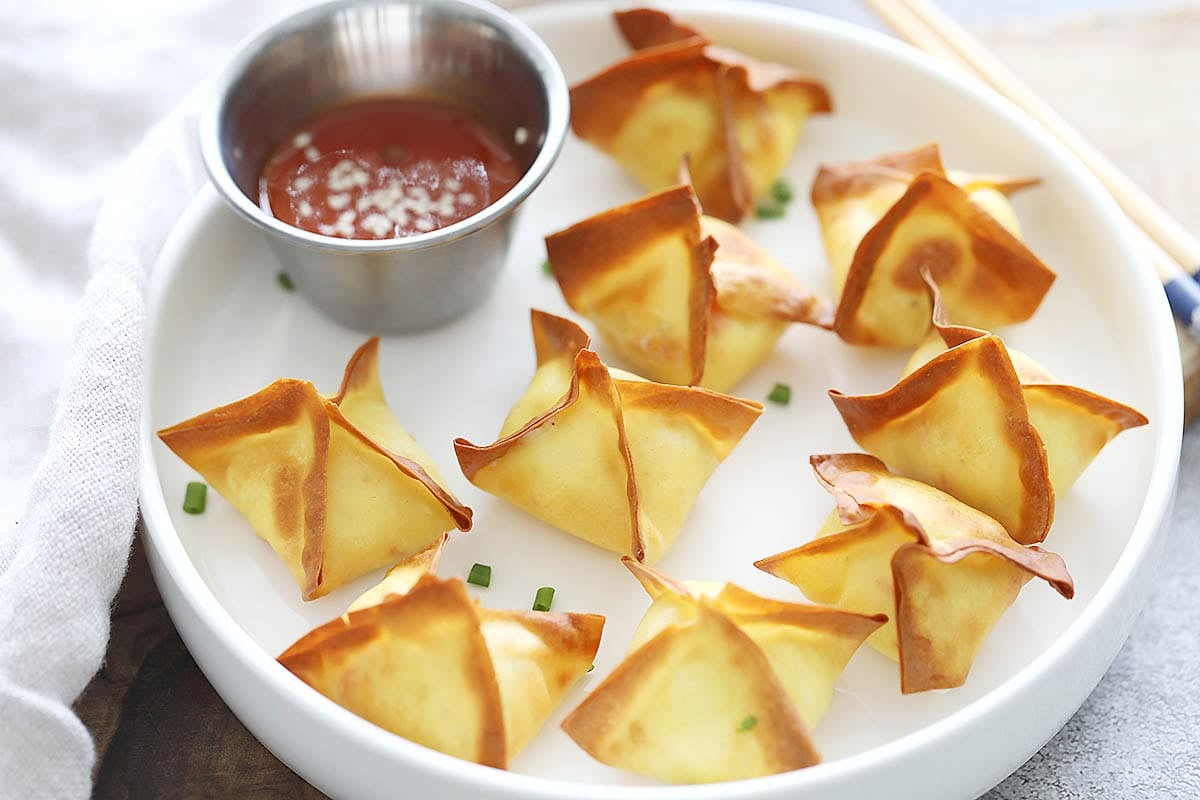Golden, crispy crab rangoon with creamy filling served on a plate.