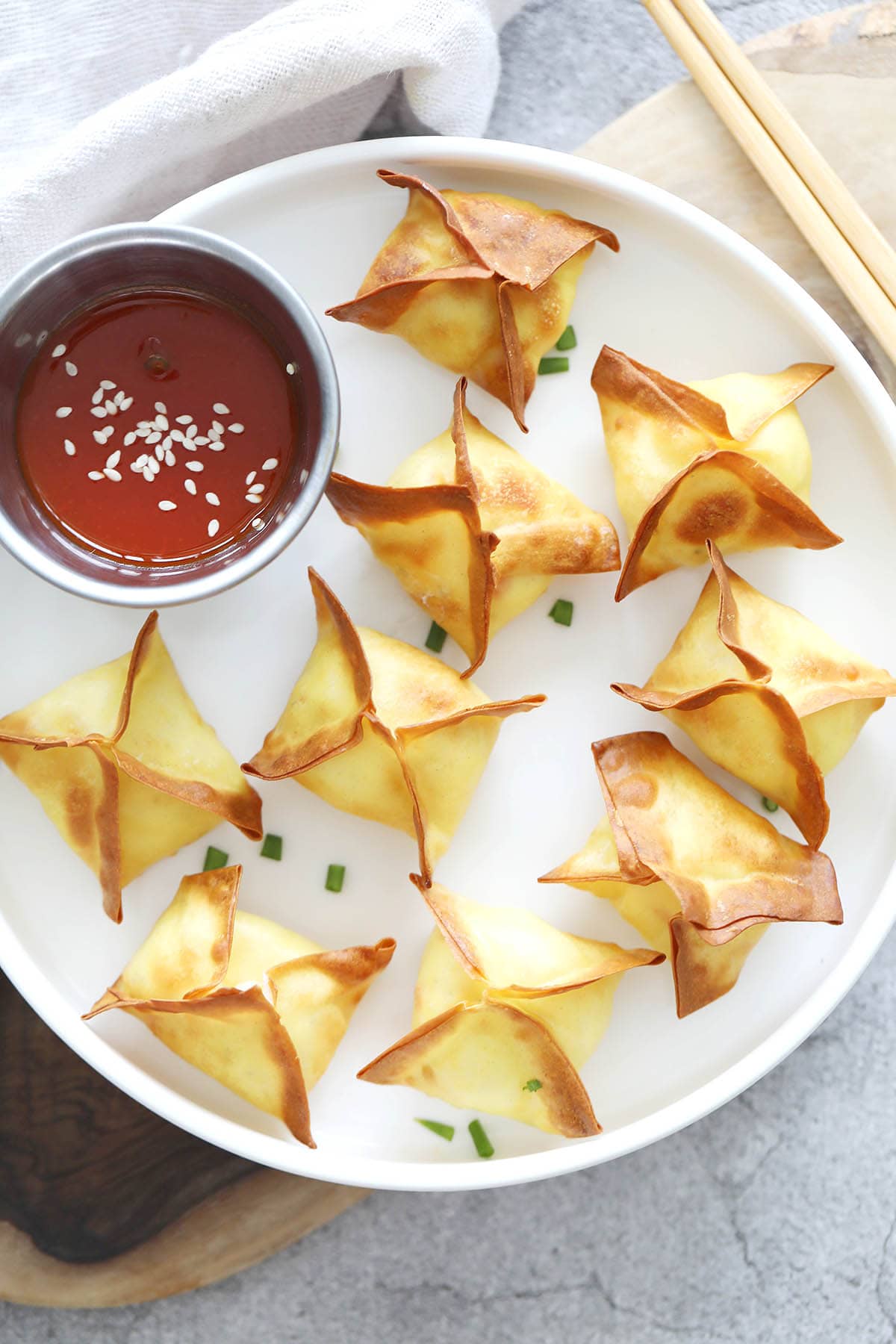 Air fryer crab rangoon served on a plate with a side of sweet and sour sauce.