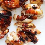 Air fryer honey chicken thighs topped with white sesame seeds, served on a plate.