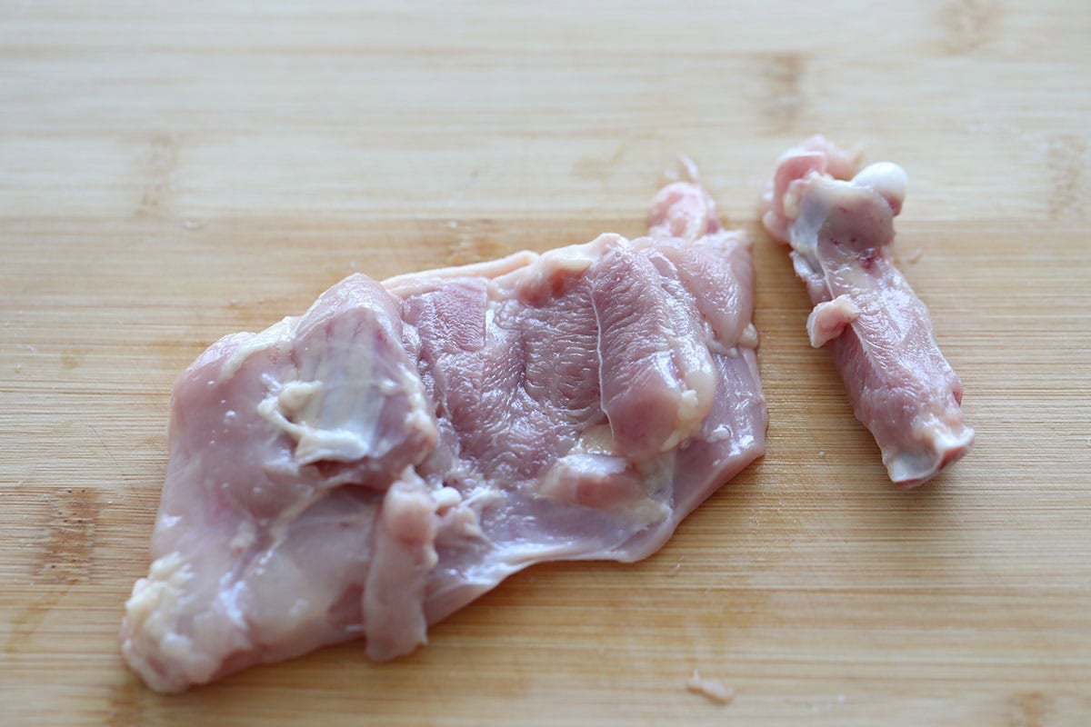 A deboned chicken thigh on a chopping board.