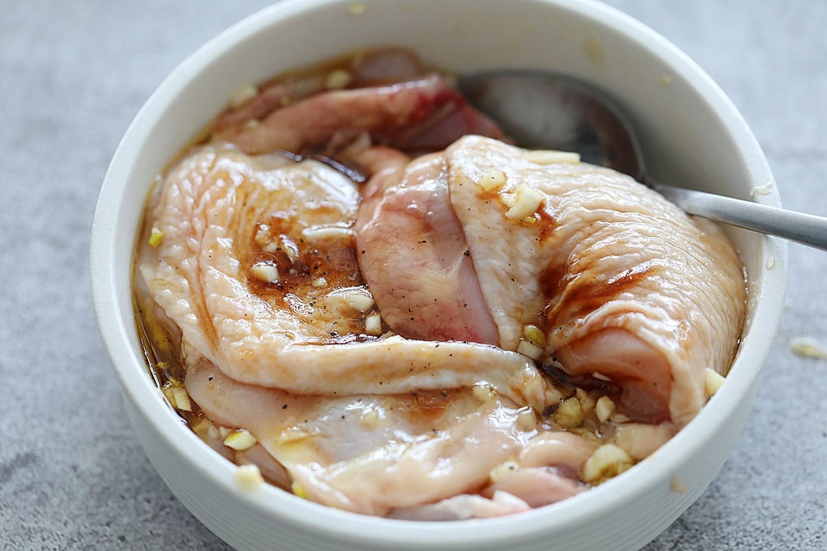 Skin-on chicken thighs in honey garlic marinade, in a bowl.