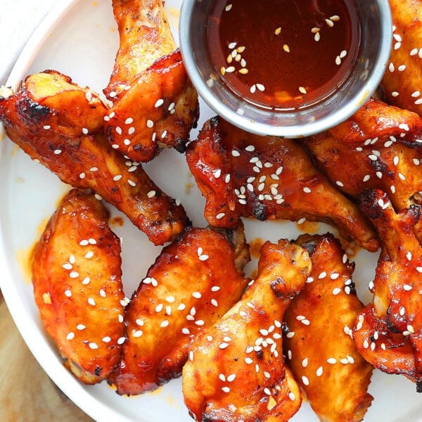 Air fryer Korean chicken wings served on a plate with a side of dripping.