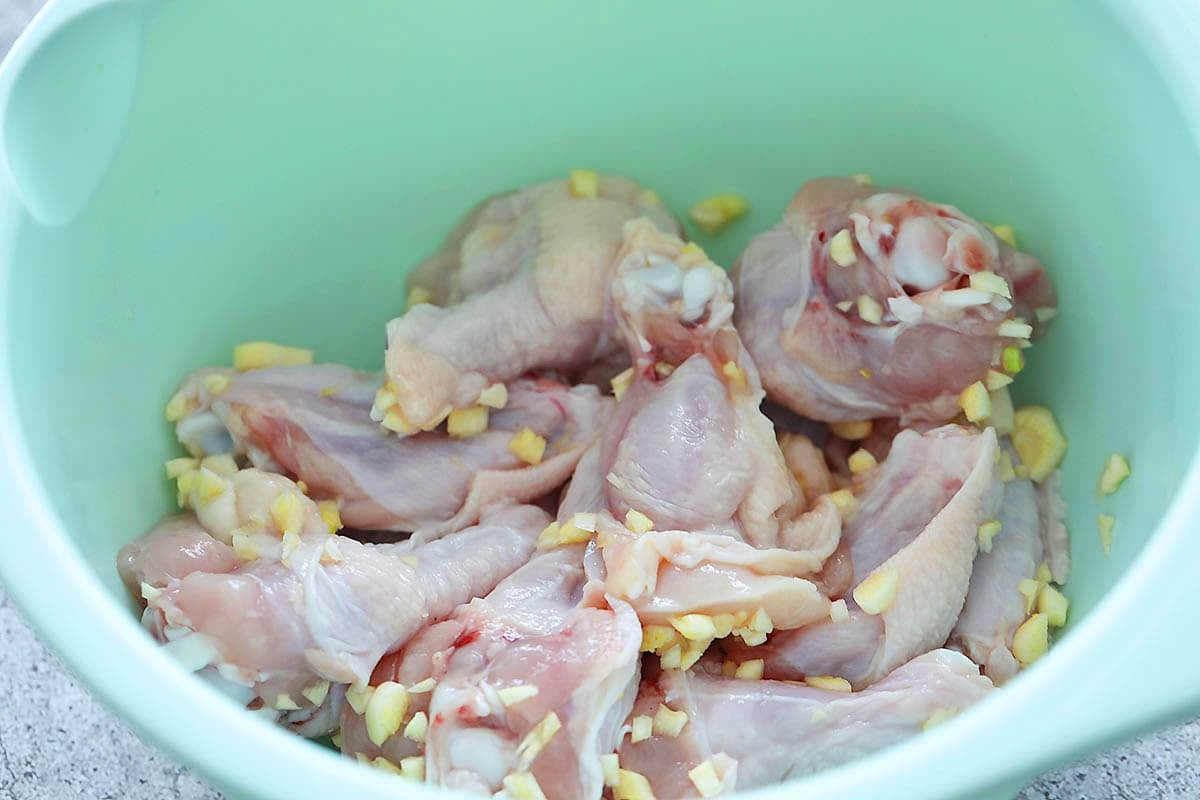 Chicken wings mixed with garlic in a bowl.