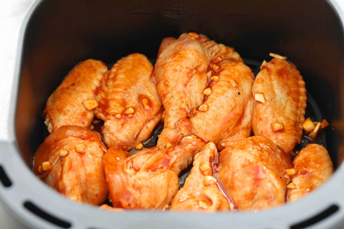 Marinated chicken wings in the air fryer basket.