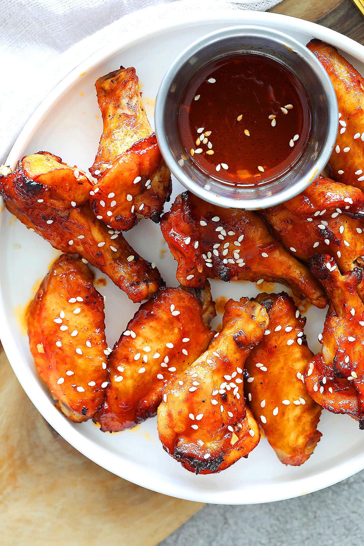 Air fryer Korean chicken wings served on a plate with a side of dripping.