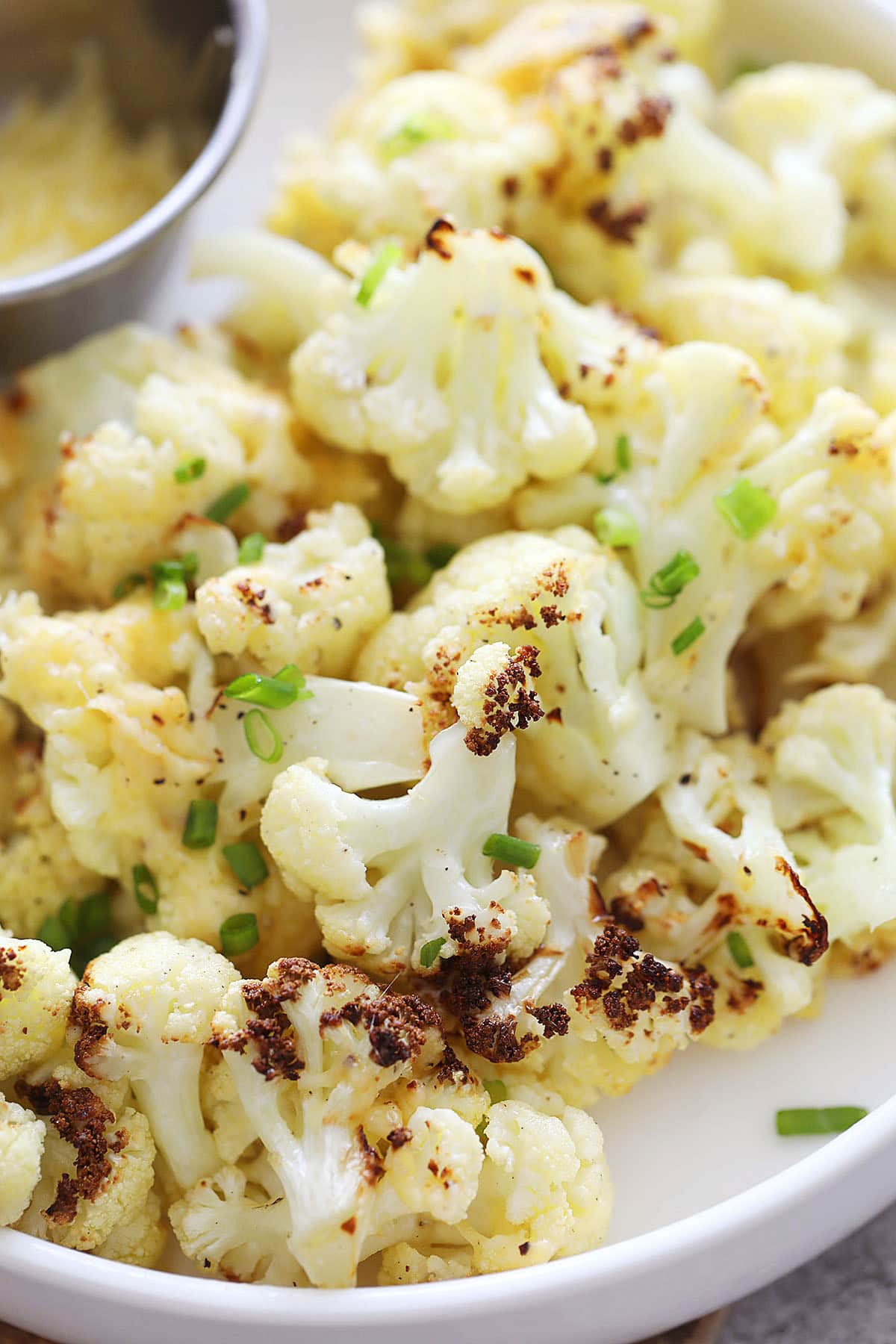Air fryer cauliflower recipe with Parmesan cheese, served with a side of extra Parmesan.