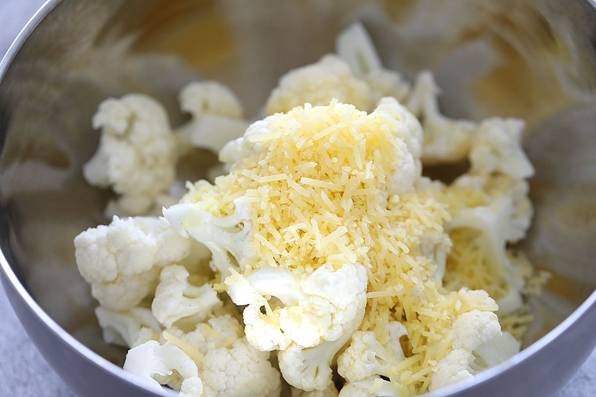 Cauliflower florets and Parmesan cheese in a bowl.